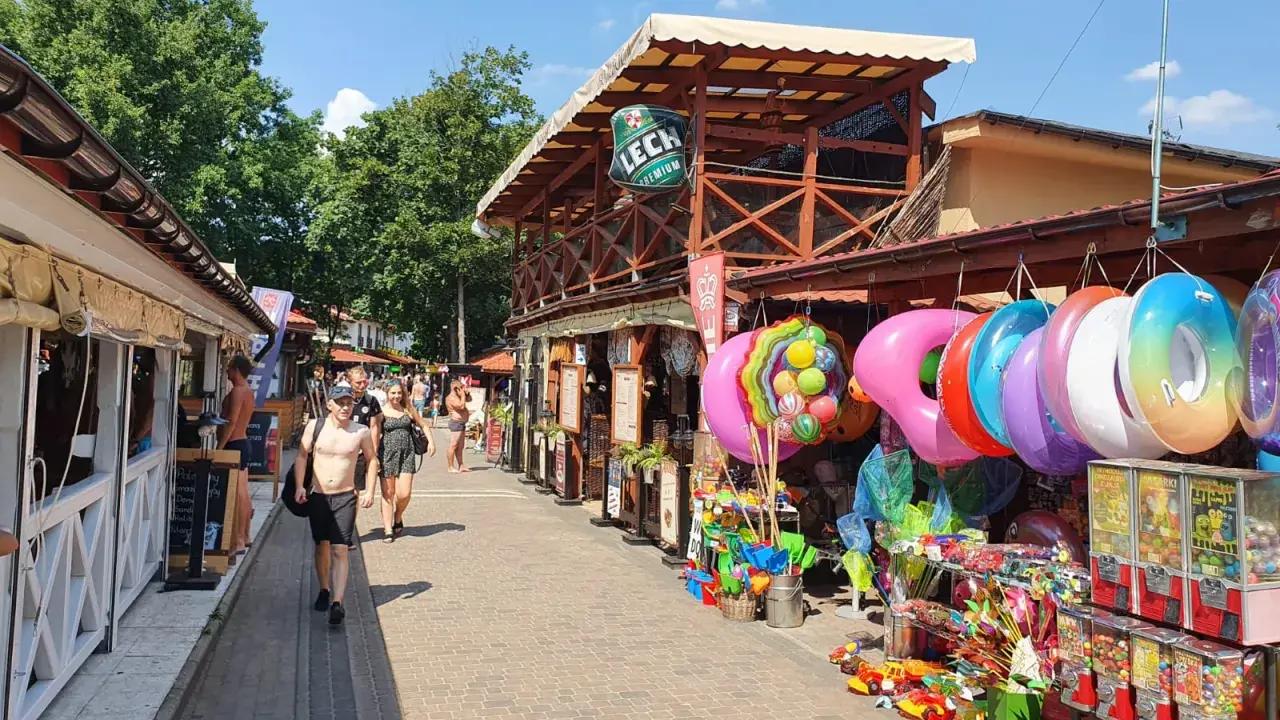 Skorzęcin atrakcje: kolorowe koła do pływania, zabawki plażowe i budki z grami na deptaku.