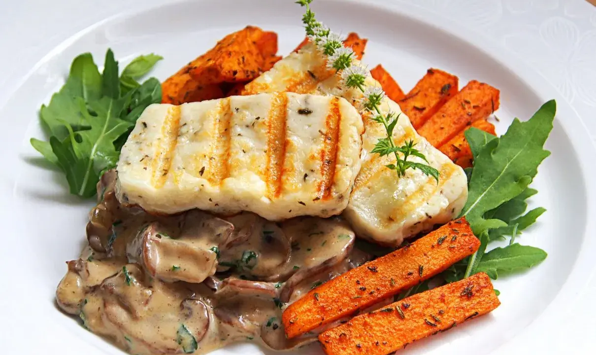 Grillowany ser halloumi z kremowym sosem grzybowym, pieczonymi batatami i rukolą.