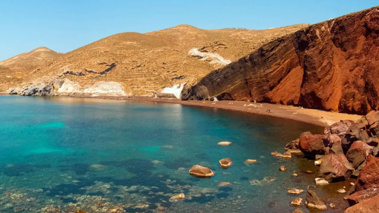 Santorini plaże: Czerwona plaża z turkusową wodą i skalistymi klifami.