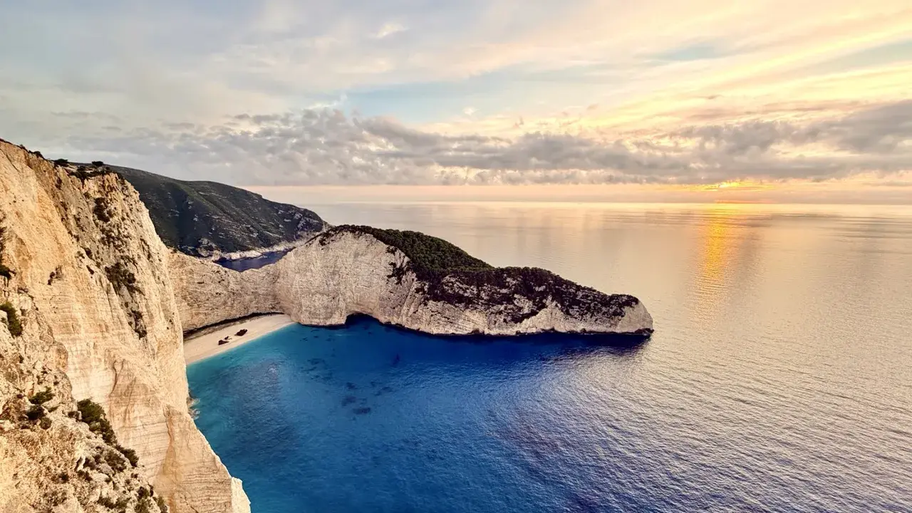 Zachód słońca nad Navagio, słynną zatoką wraku na Zakynthos. Białe klify, turkusowa woda i wrak statku tworzą malowniczy krajobraz.