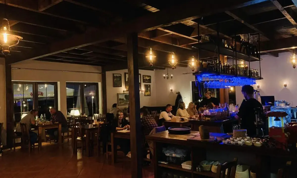 Wnętrze restauracji z ludźmi przy stołach i barem.