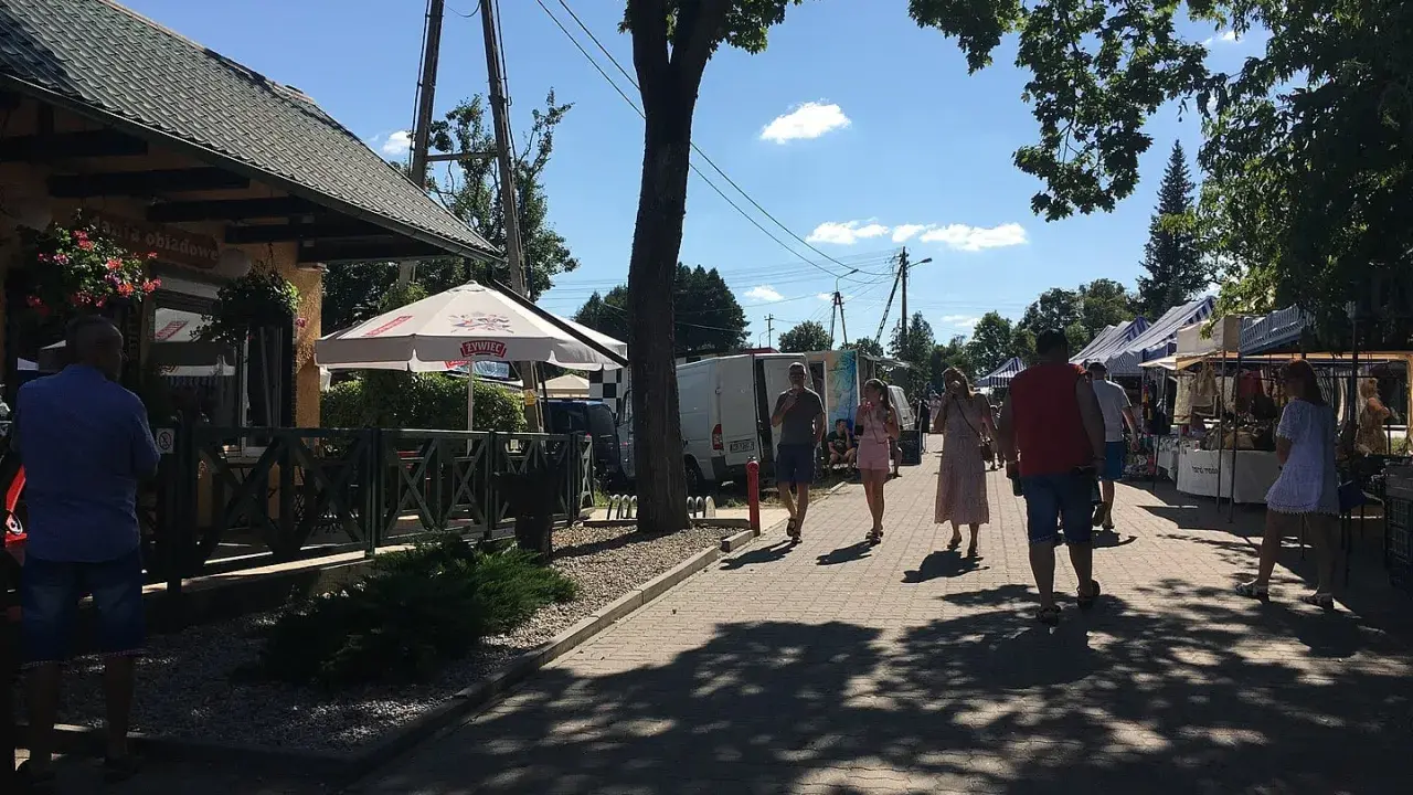 Spacer po targu w upalny dzień. Ludzie oglądają stoiska, szukając lokalnych produktów i pamiątek. Tleń atrakcje oferują wiele możliwości spędzenia wolnego czasu.
