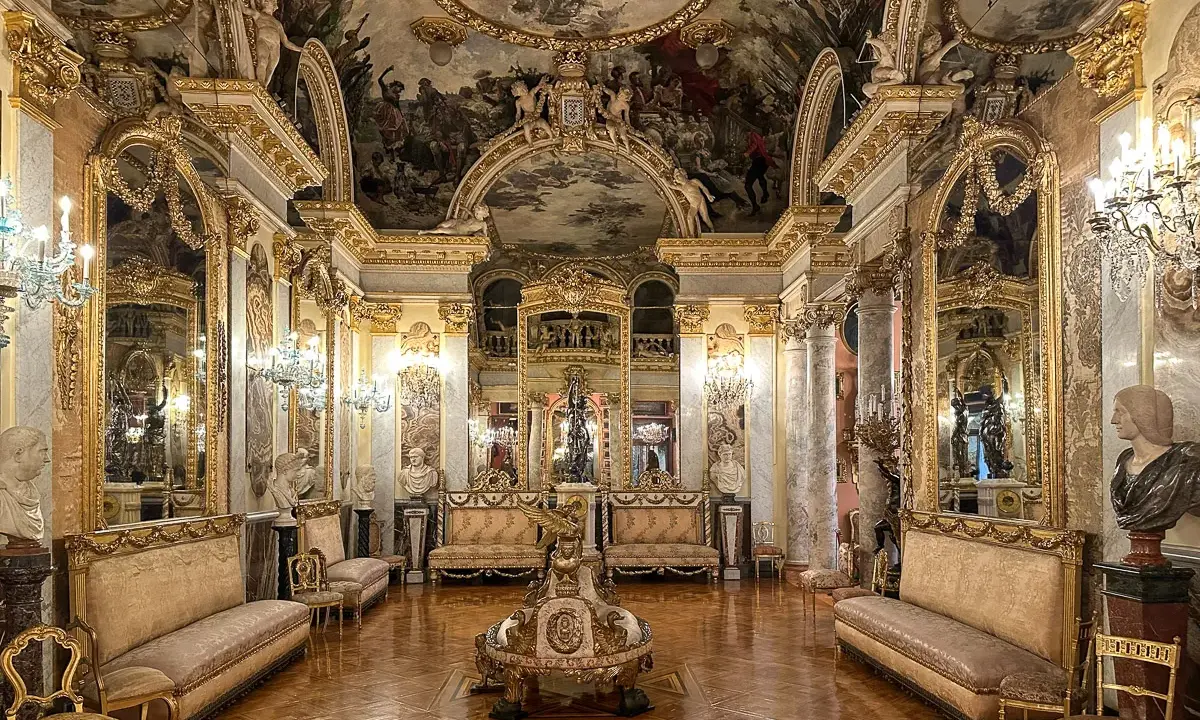 Złocone wnętrze muzeum w Madrycie, z malowanym sufitem, lustrami i antycznymi meblami.