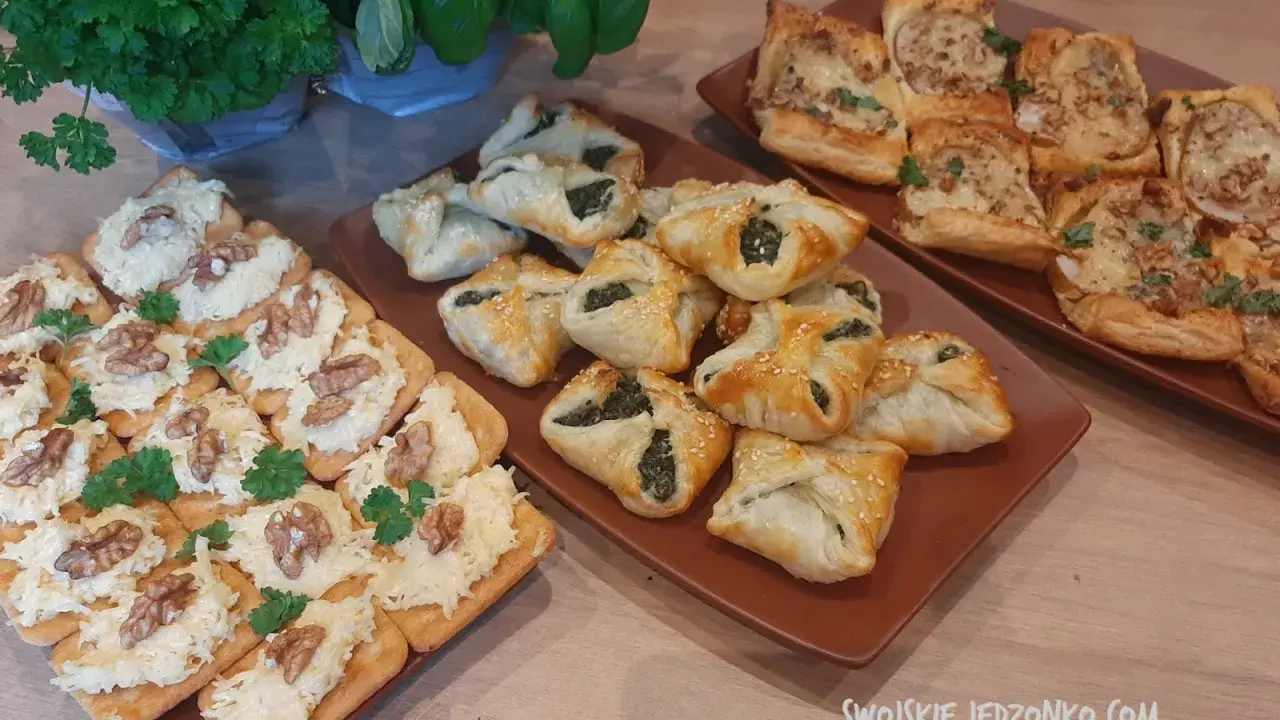 Na stole trzy rodzaje przekąsek: krakersy z pastą serową i orzechami, pieczone ciastka z nadzieniem szpinakowym i kwadratowe tartaletki z farszem. Idealna szybka przekąska na imprezę.