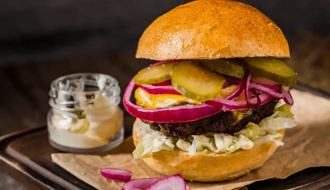 Pyszny burger z soczystą wołowiną, chrupiącą sałatą, piklami, czerwoną cebulą i majonezem. Idealny na prawdziwe burgery przepis.