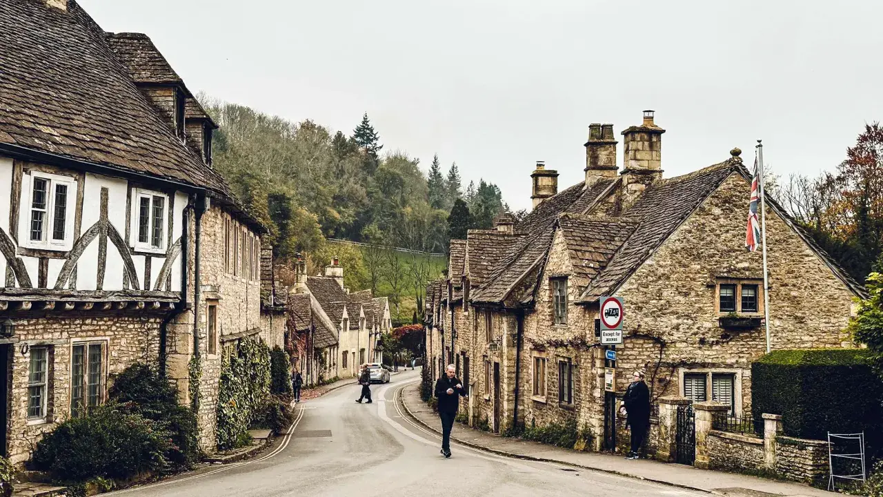 Kamienna uliczka w Cotswolds, z tradycyjnymi domami i drzewami na wzgórzach.
