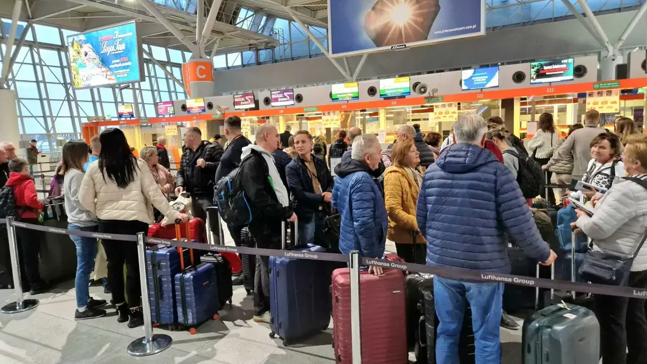 Kolejka do odprawy na jednym z największych lotnisk w Polsce. Pasażerowie z bagażami czekają na swoją kolej.