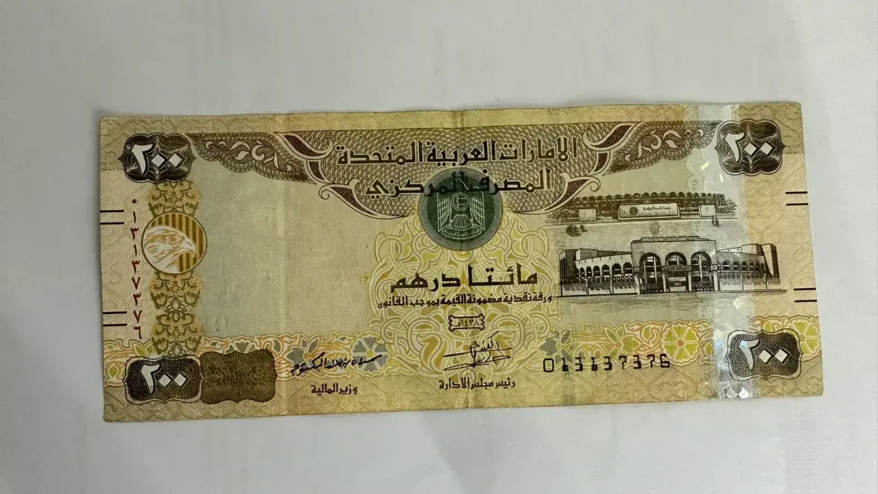 Banknot 200 dirhamów, waluta w Dubaju, z wizerunkiem sokoła i budynków.