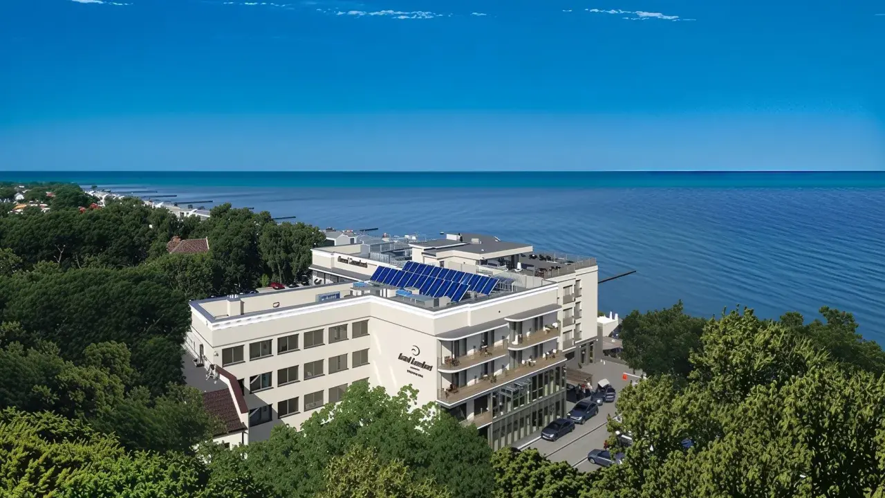 Nowoczesny hotel z panelami słonecznymi nad polskim morzem, otoczony zielenią.