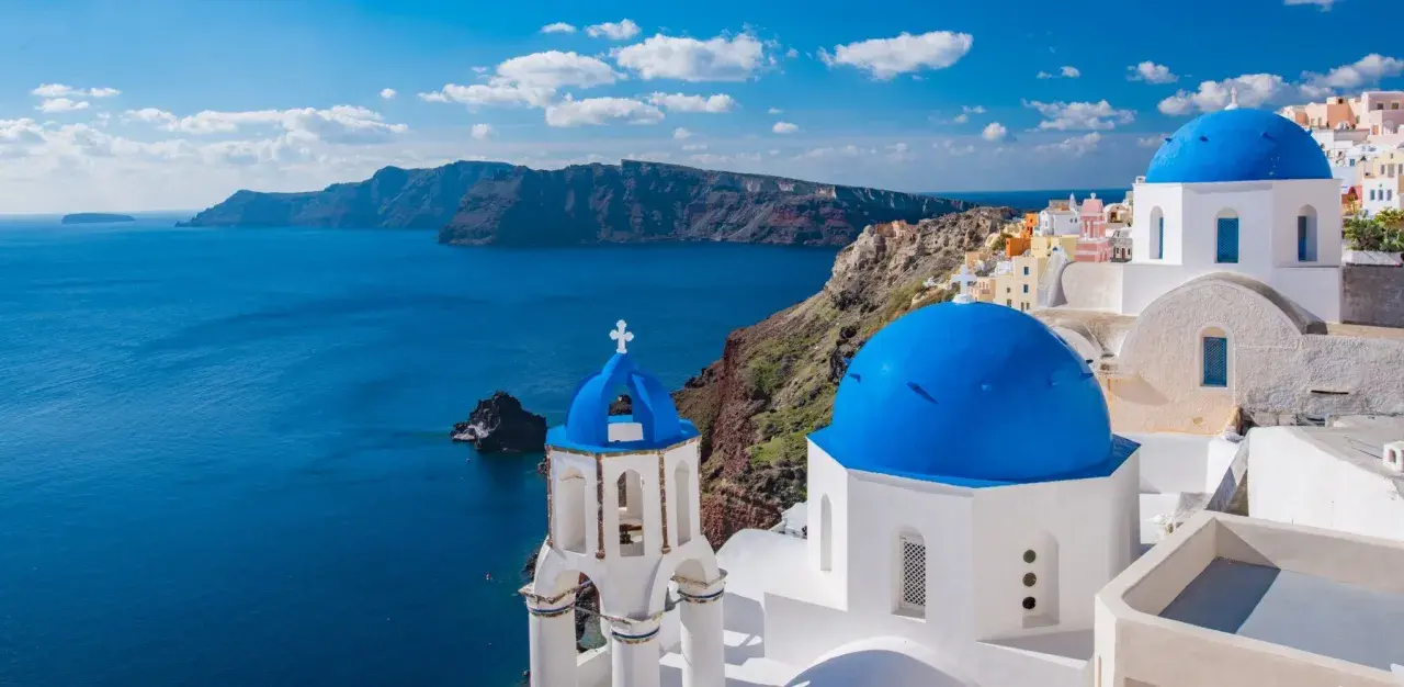 Santorini, Grecja. Białe domy z niebieskimi kopułami na tle morza. Ciekawe miejsca i widoki.