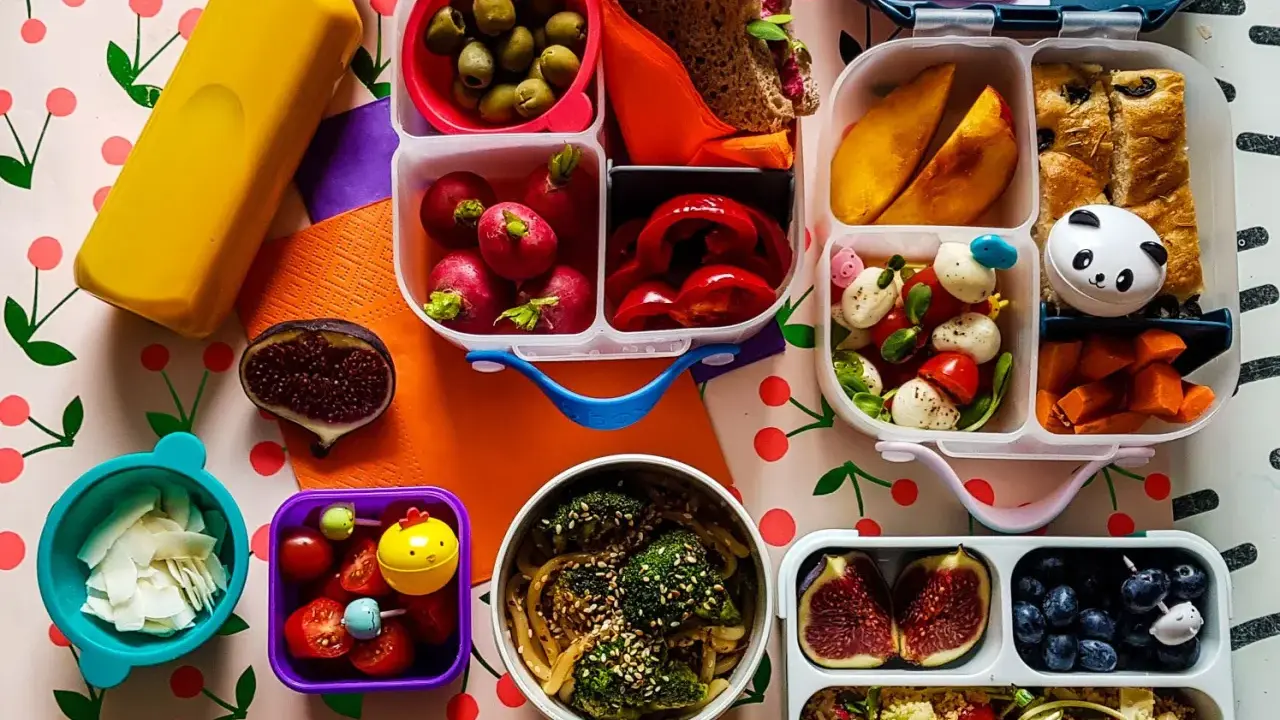Kolorowy lunchbox z owocami, warzywami, kanapką i słodkościami to idealne szybkie śniadanie dla dzieci.