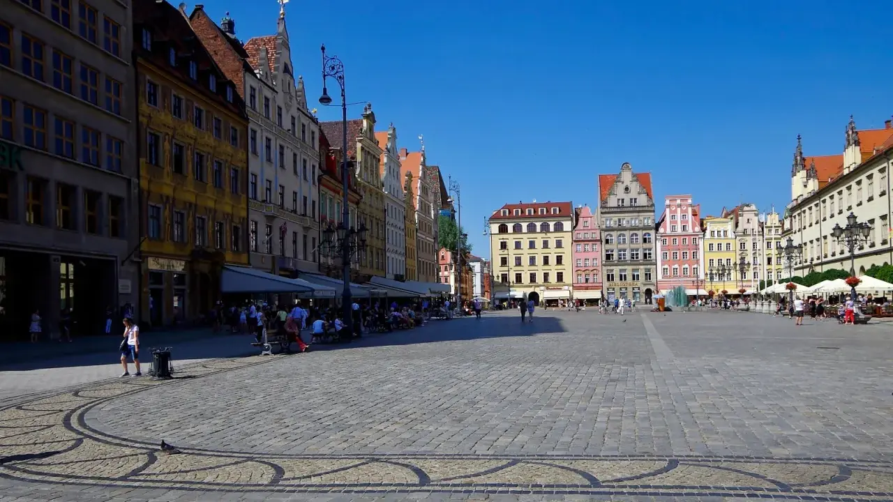 Kolorowy Rynek we Wrocławiu, idealne miejsce na jednodniowe wycieczki z Wrocławia. Ludzie spacerują, siedzą w kawiarniach, ciesząc się słońcem.