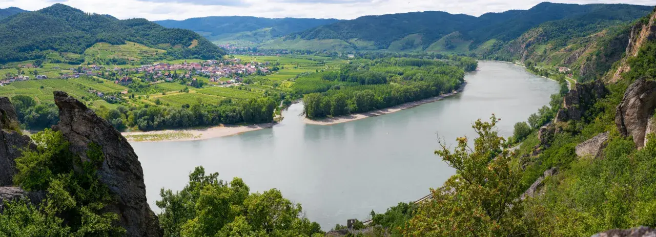 Malownicza dolina Wachau z wijącą się rzeką, zielonymi winnicami i uroczą wioską.