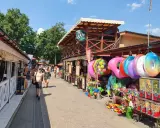 Skorzęcin atrakcje: kolorowe koła do pływania, zabawki plażowe i budki z grami na deptaku.