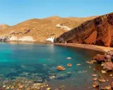 Santorini plaże: Czerwona plaża z turkusową wodą i skalistymi klifami.
