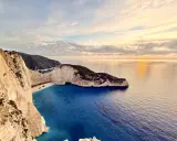Zachód słońca nad Navagio, słynną zatoką wraku na Zakynthos. Białe klify, turkusowa woda i wrak statku tworzą malowniczy krajobraz.