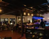 Wnętrze restauracji z ludźmi przy stołach i barem.