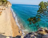 Piękna plaża w Albanii z turkusową wodą i rzędami parasoli. Ceny wakacji w Albanii są przystępne, a widoki zachwycające.