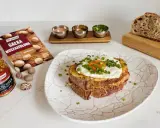 Pyszny croque madame z jajkiem sadzonym i szczypiorkiem, obok musztarda francuska i gałka muszkatołowa.