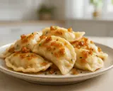 Pyszne pierogi ruskie, jak u babci, polane skwarkami i posypane szczypiorkiem.