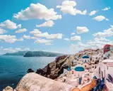 Santorini, Grecja. Białe domy z niebieskimi kopułami kościołów na zboczu góry, widok na morze. Zastanawiasz się, ile się leci do Grecji?