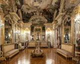 Złocone wnętrze muzeum w Madrycie, z malowanym sufitem, lustrami i antycznymi meblami.