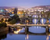 Praga nocą, z licznymi mostami na Wełtawie i oświetlonymi budynkami. Ciekawe ciekawostki o Czechach czekają na odkrycie w tym magicznym mieście.