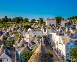 Urokliwe trulli w Alberobello, z ich stożkowymi dachami, tworzą bajkowy krajobraz pod błękitnym niebem.