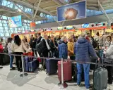 Kolejka do odprawy na jednym z największych lotnisk w Polsce. Pasażerowie z bagażami czekają na swoją kolej.