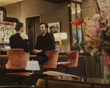 Para w eleganckim barze w Warszawie, uśmiechnięci, siedzą na aksamitnych stołkach. Idealna randka w stolicy.