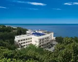 Nowoczesny hotel z panelami słonecznymi nad polskim morzem, otoczony zielenią.