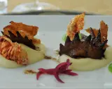 Wykwintne włoskie dania: kremowe purée, chrupiące krewetki i ciemne grzyby, ozdobione zielonym sosem i marynowaną czerwoną cebulą.