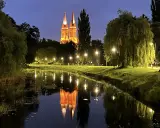Wieczorny spacer nad rzeką we Włocławku. Podświetlona katedra odbija się w wodzie, tworząc magiczny widok. Idealne włocławek atrakcje na weekend.