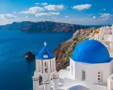 Santorini, Grecja. Białe domy z niebieskimi kopułami na tle morza. Ciekawe miejsca i widoki.