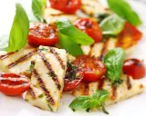 Grillowany serek halloumi z pomidorkami koktajlowymi i bazylią, apetyczna przekąska.