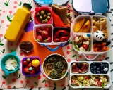 Kolorowy lunchbox z owocami, warzywami, kanapką i słodkościami to idealne szybkie śniadanie dla dzieci.