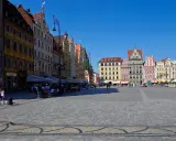 Kolorowy Rynek we Wrocławiu, idealne miejsce na jednodniowe wycieczki z Wrocławia. Ludzie spacerują, siedzą w kawiarniach, ciesząc się słońcem.