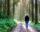 Kobieta w kapeluszu spaceruje leśną ścieżką. Idealne miejsce, gdzie na spacer w Warszawie, by poczuć spokój natury.