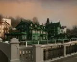 Krynica-Zdrój atrakcje wieczorem: malownicza, zielona willa z restauracją i hotel Mewą w mglistym, jesiennym krajobrazie.