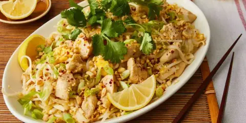 Pyszne pad thai co to? Danie z kurczakiem, makaronem ryżowym, orzeszkami ziemnymi i świeżą kolendrą, podane z cytryną.