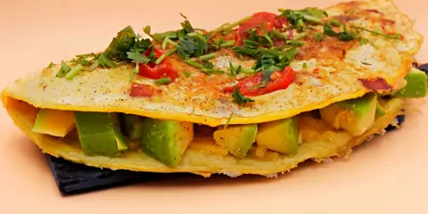 Omlet z awokado, pomidorkami i ziołami, pyszne i zdrowe śniadanie.