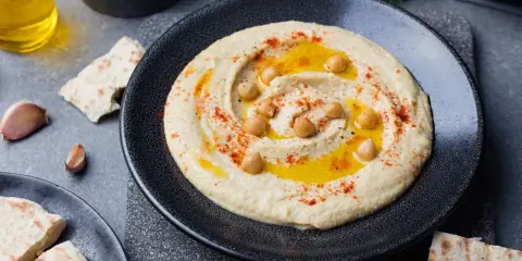 Pyszny, kremowy hummus co to jest? To pasta z ciecierzycy, oliwy, czosnku i przypraw, podana z pitą.