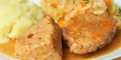 Soczysta pieczeń z szynki wieprzowej w sosie, podana z ziemniakami i kapustą. Pyszny obiad!