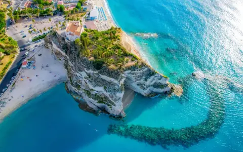 Widok z lotu ptaka na skaliste klify i piaszczyste plaże Kalabrii, z turkusową wodą Morza Śródziemnego.