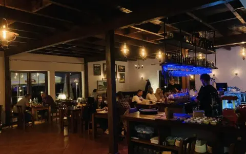 Wnętrze restauracji z ludźmi przy stołach i barem.