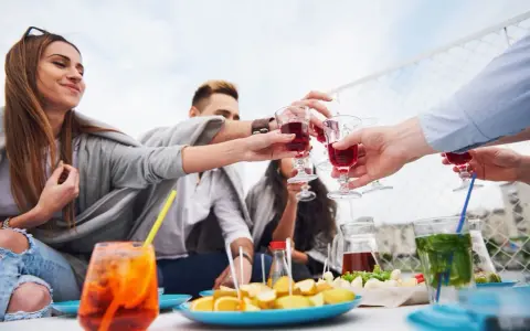 Grupa przyjaciół wznosi toast aperitifem, ciesząc się spotkaniem.