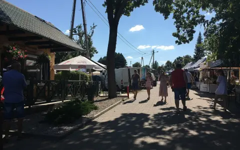 Spacer po targu w upalny dzień. Ludzie oglądają stoiska, szukając lokalnych produktów i pamiątek. Tleń atrakcje oferują wiele możliwości spędzenia wolnego czasu.
