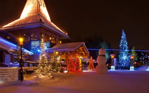 Magiczna noc w Wiosce Świętego Mikołaja. Ośnieżone domki, choinki rozświetlone lampkami i bałwan tworzą świąteczną atmosferę.