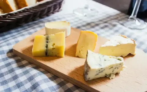 Deska z różnymi rodzajami serów, w tym ser włoski z niebieską pleśnią, idealny na degustację.