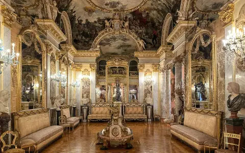 Złocone wnętrze muzeum w Madrycie, z malowanym sufitem, lustrami i antycznymi meblami.